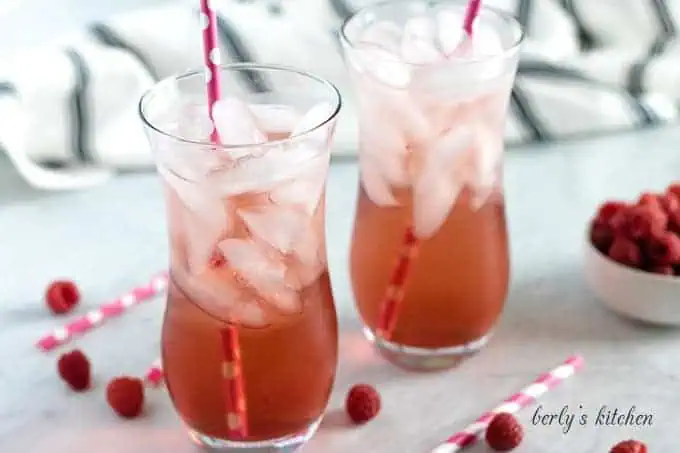 Two glasses of raspberry italian soda with pink straws.