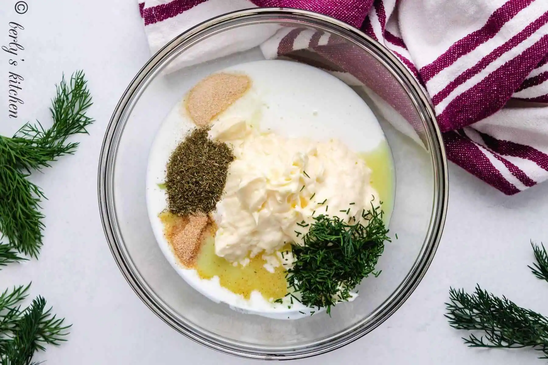 Top down view of ingredients for dill dressing in a glass bowl.