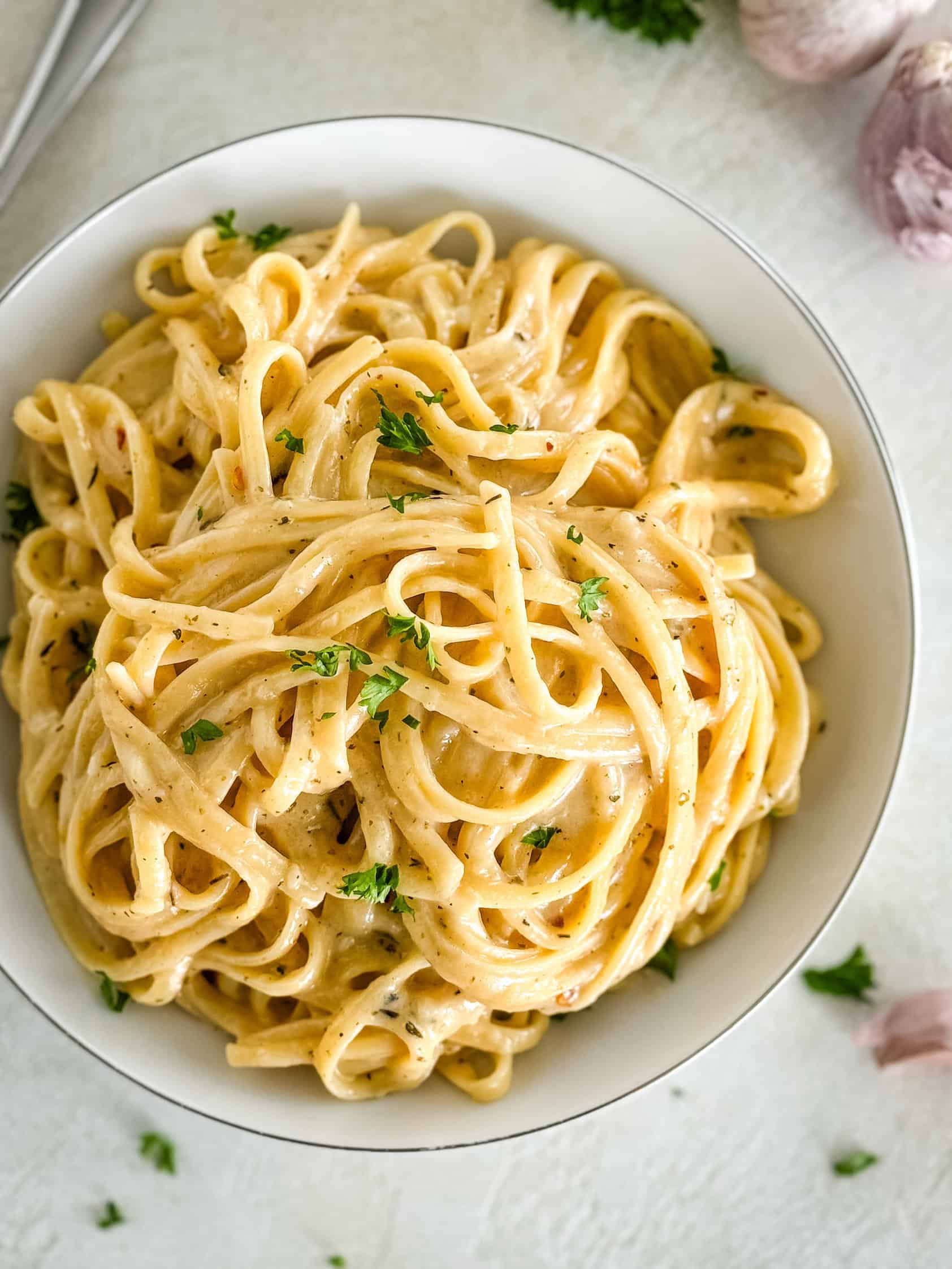 Overhead shot of a bowl of creamy pasta garnished with parsley.