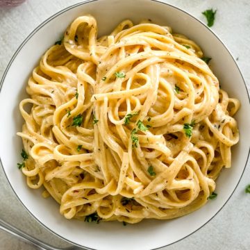 A close-up view of creamy pasta topped with fresh parsley.