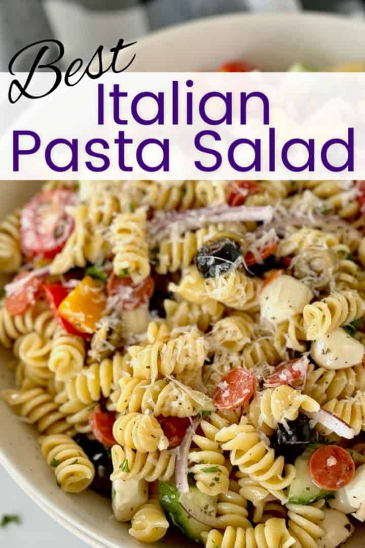 Best italian pasta salad: a close-up of a delicious salad with rotini, cherry tomatoes, bell peppers, black olives, cucumber, red onion, and mozzarella cheese balls, sprinkled with grated parmesan.