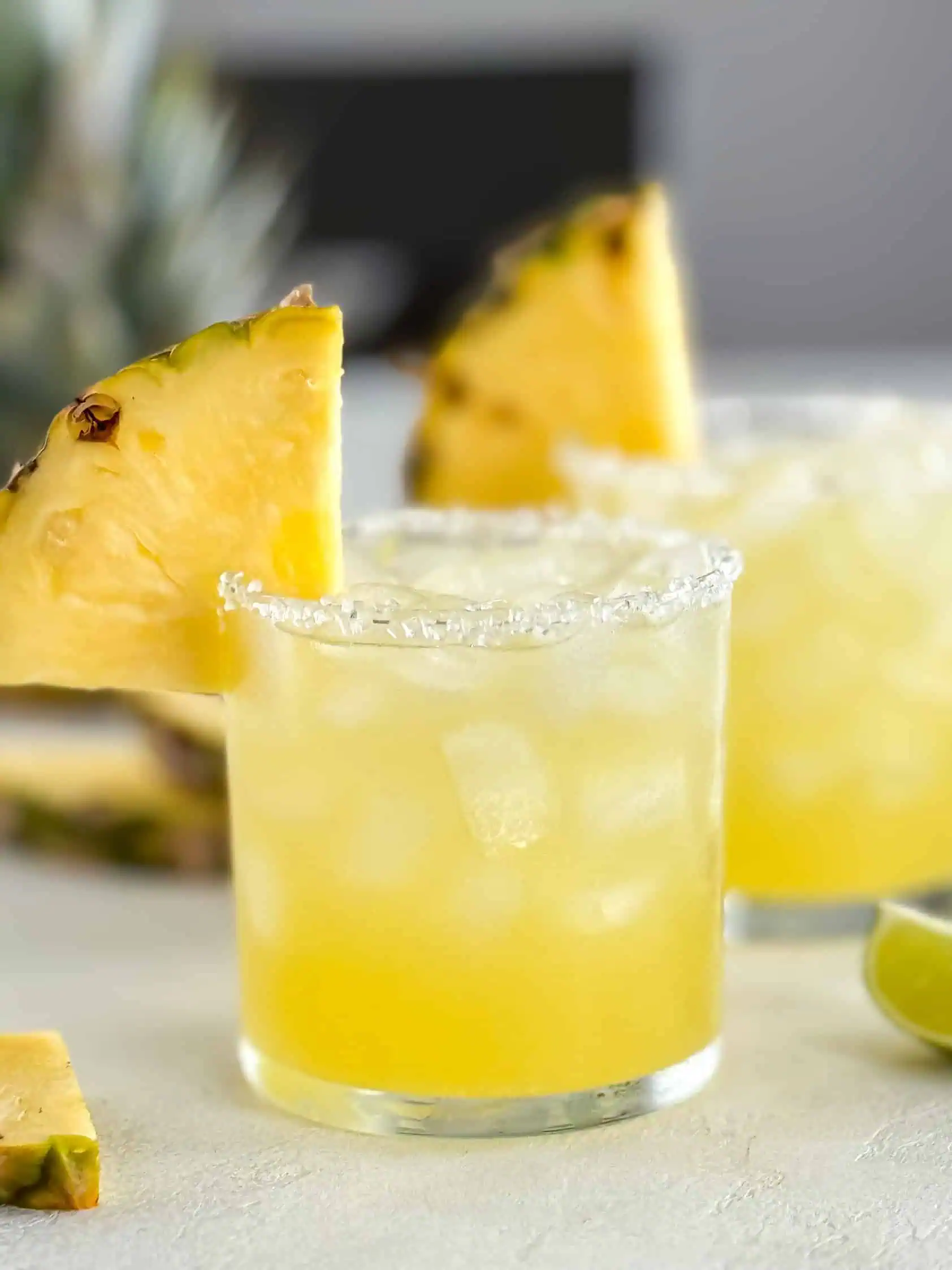 Two refreshing drinks with salted rims and pineapple slices, ready to be enjoyed.