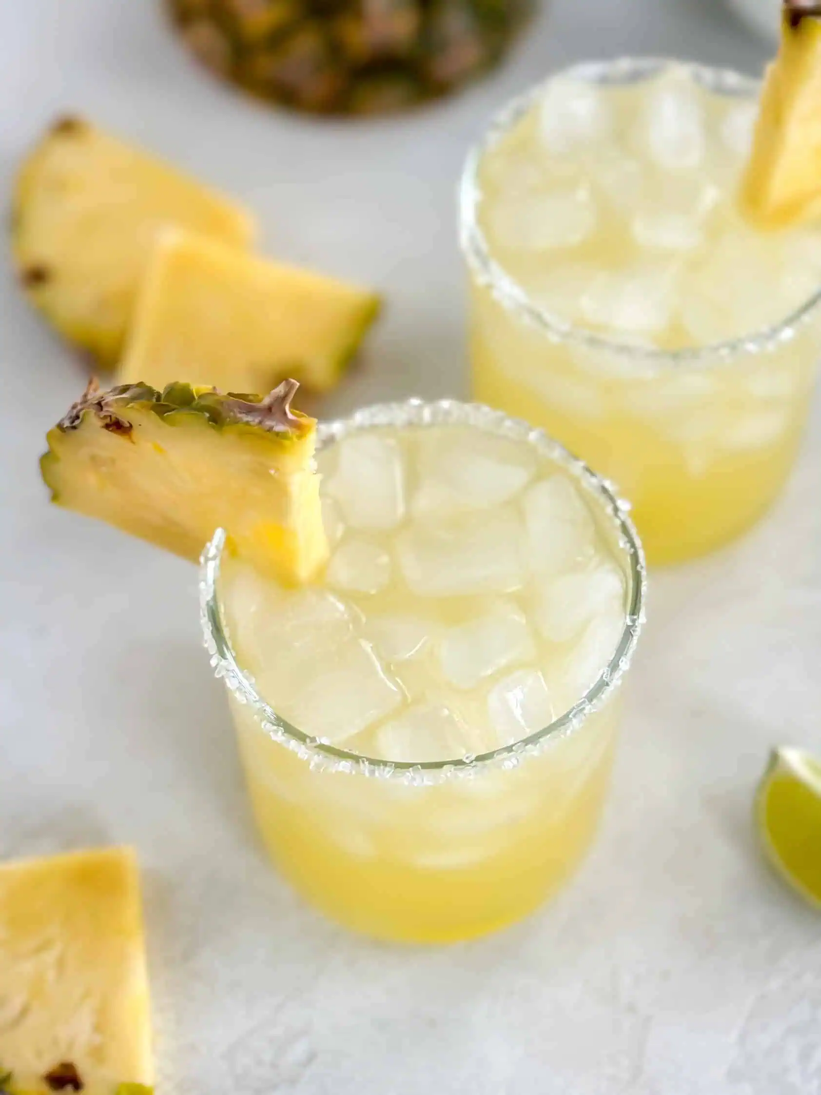 Overhead shot of two ice-filled glasses garnished with pineapple slices.