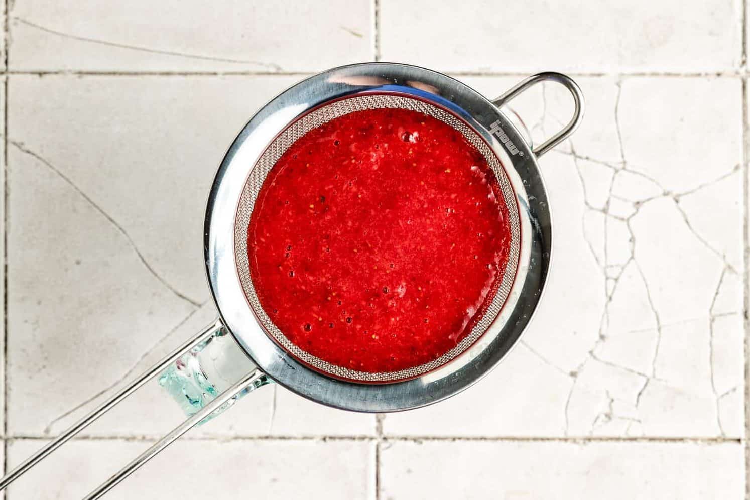 Strawberry puree poured into a mesh sieve.
