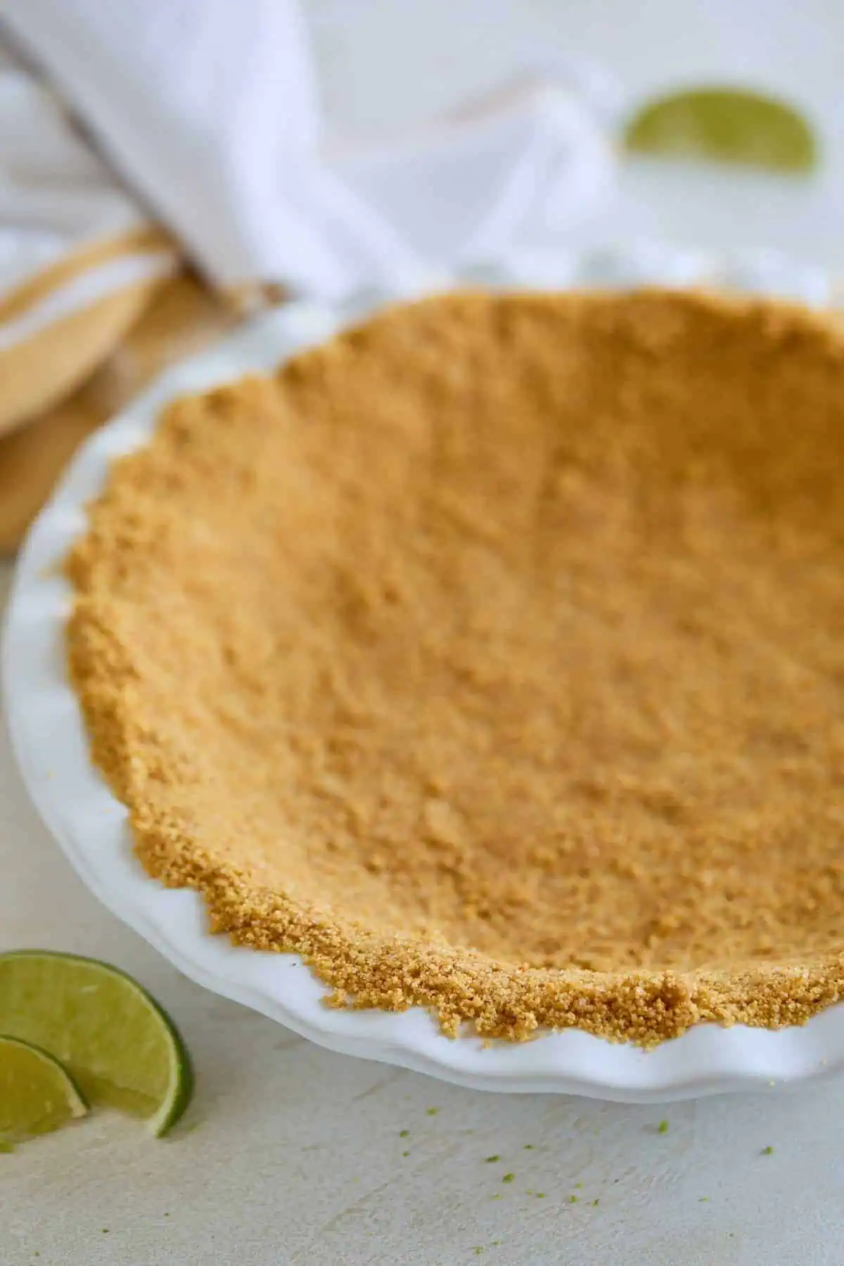 A prepared graham cracker crust in a white pie dish.