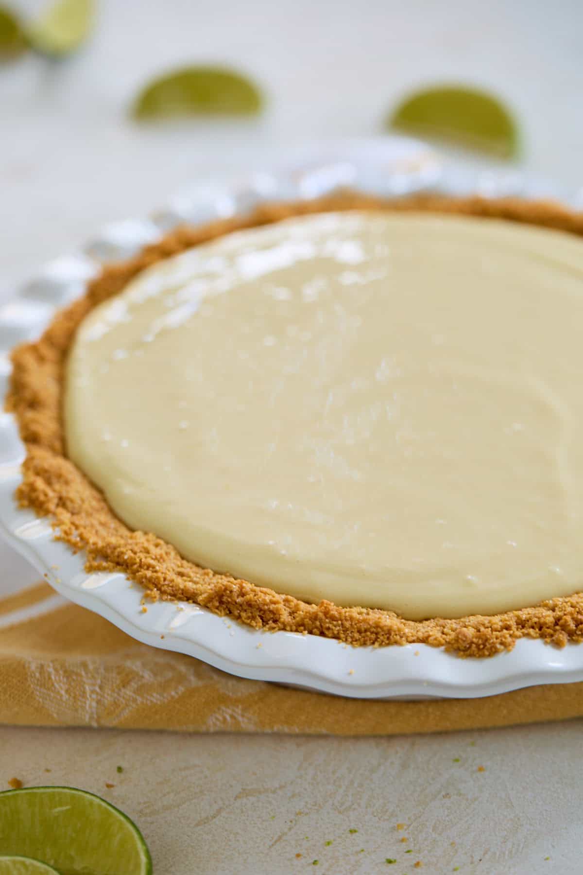 Unbaked key lime pie filling poured into the graham cracker crust, ready to be baked.