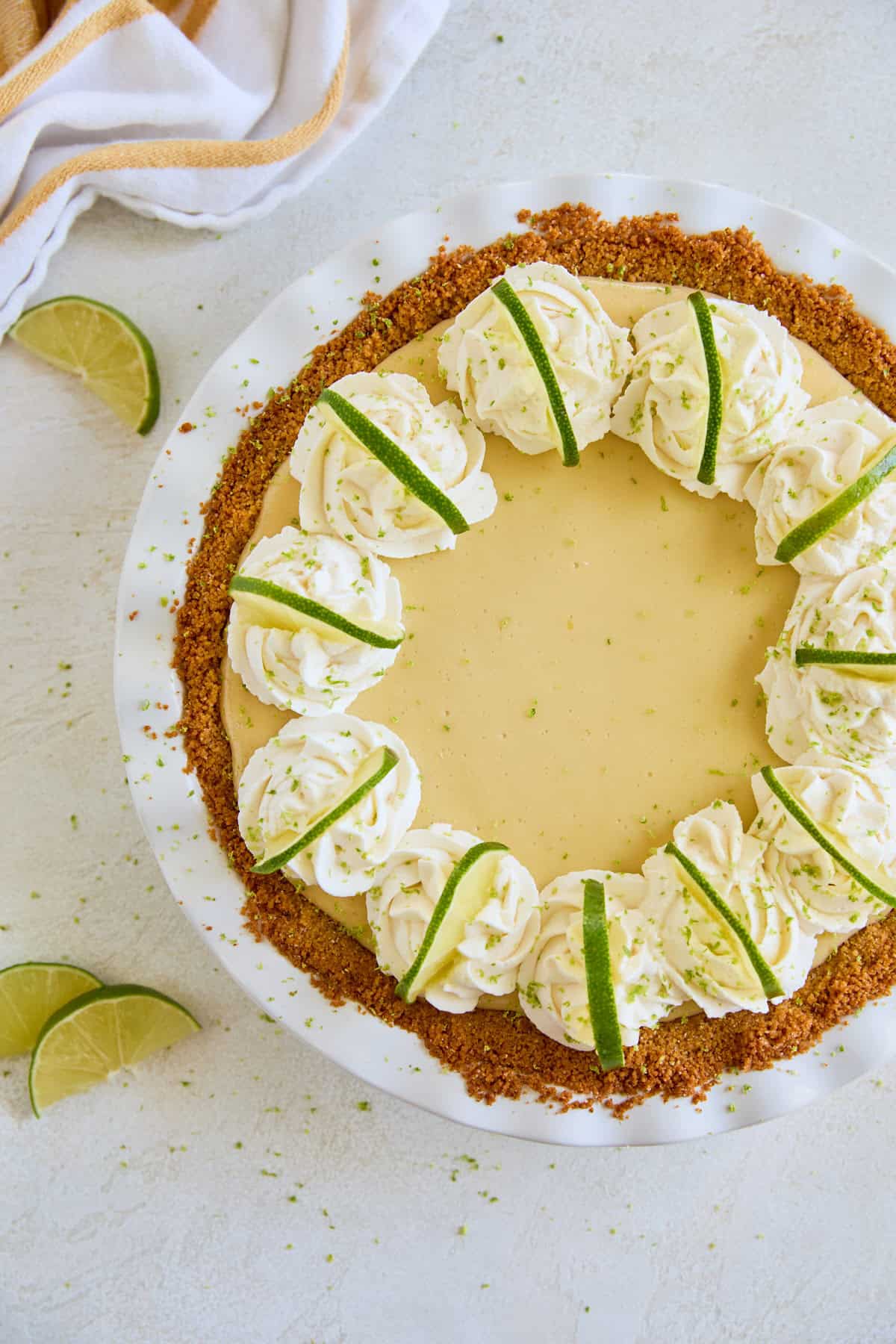 Pie topped with piped whipped cream and lime slices, viewed from above.