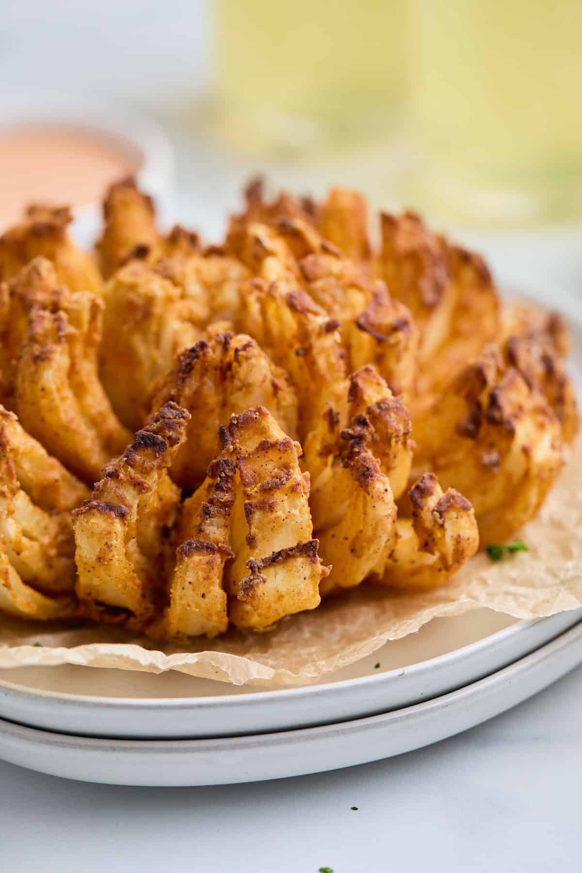 Side view of a golden brown air fryer blooming onion, showing its crispy layers.