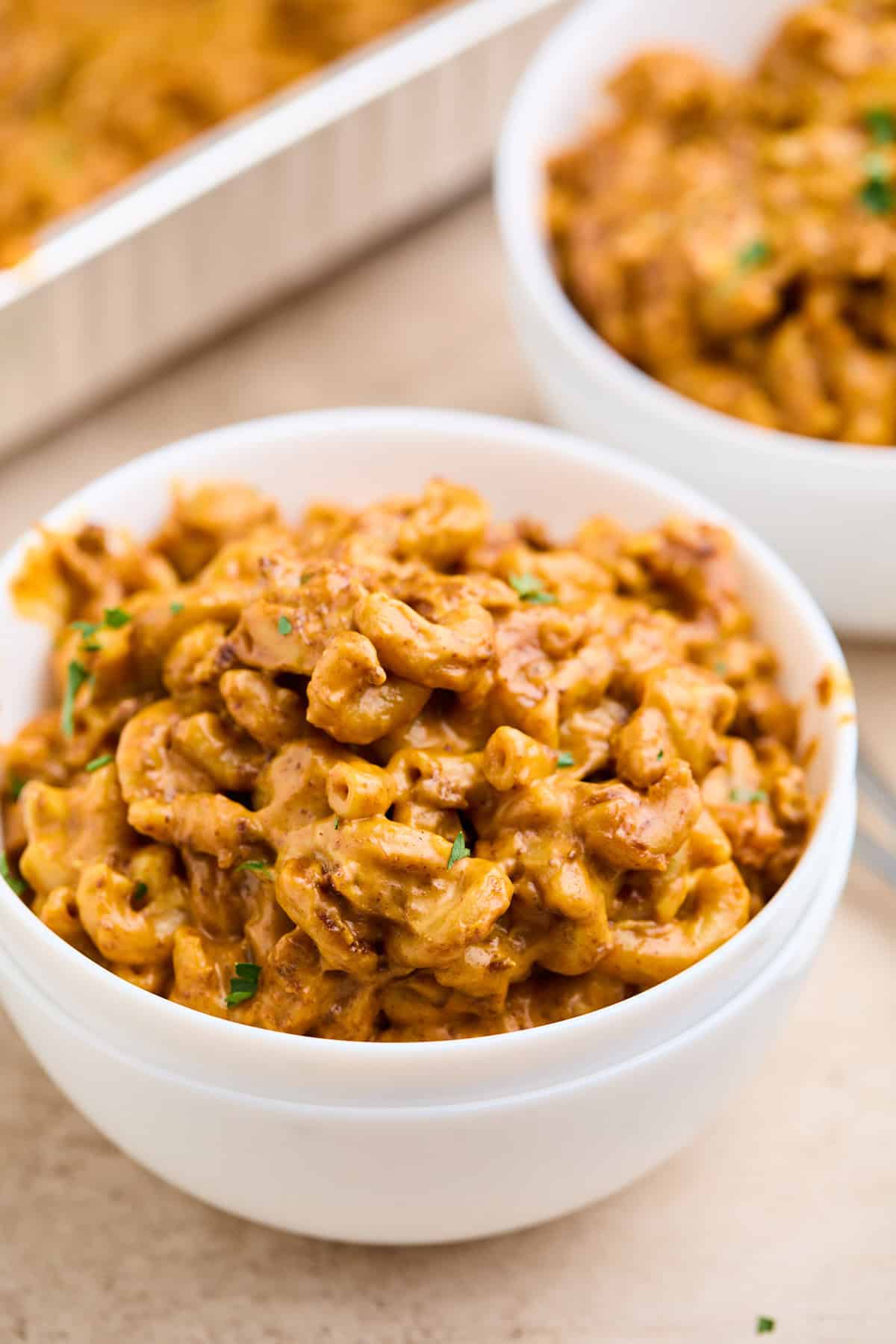 A close-up of cheesy chili mac served in a white bowl.