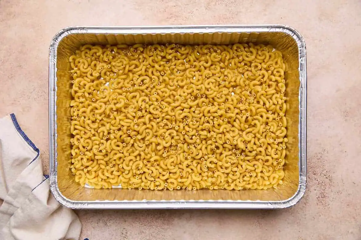 A baking dish filled with uncooked elbow macaroni.