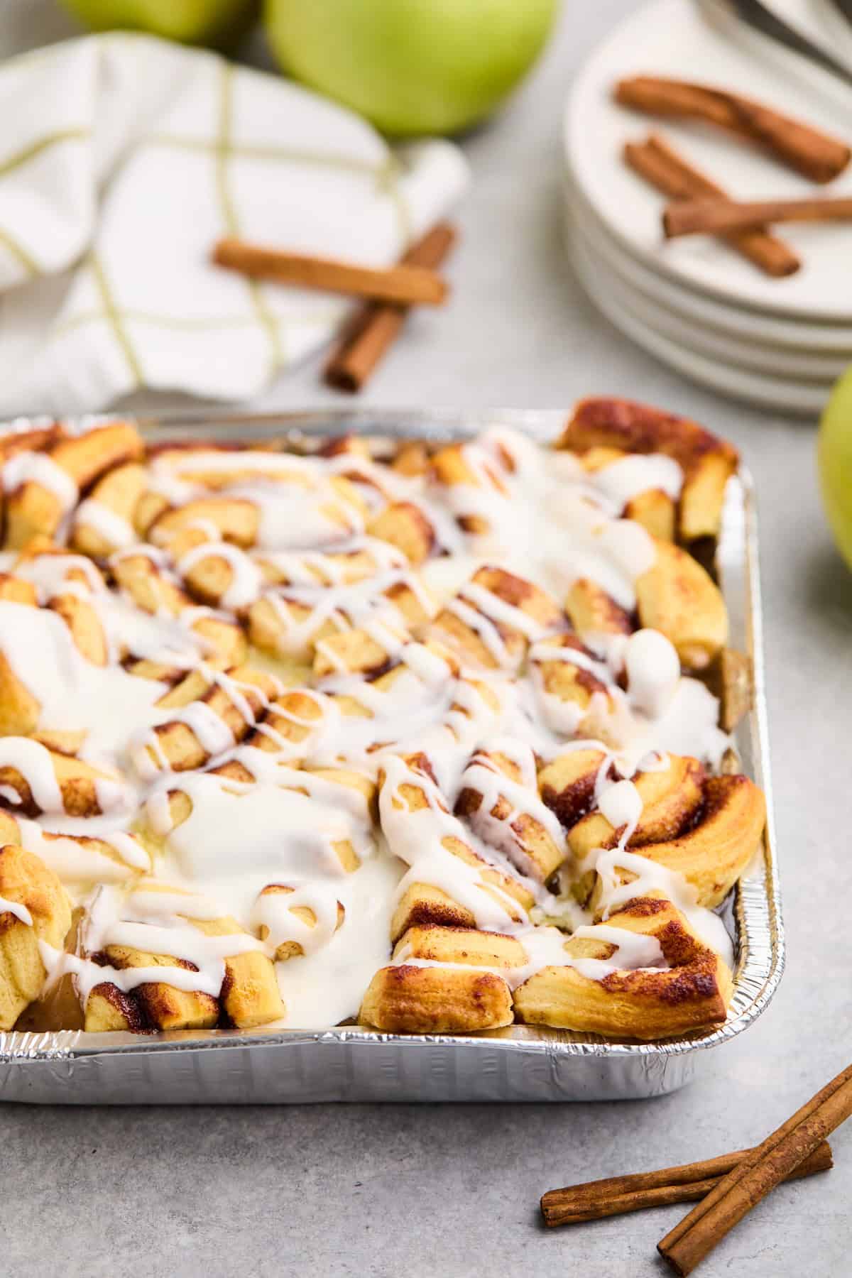 Freshly baked cinnamon roll apple cobbler with icing drizzle in a baking dish.