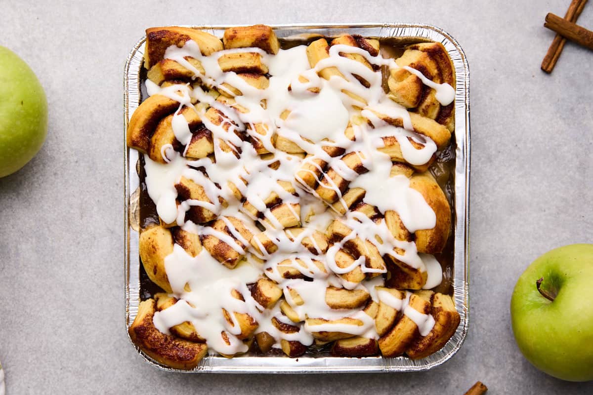 Cinnamon rolls with apple pie filling freshly baked and drizzled with icing.