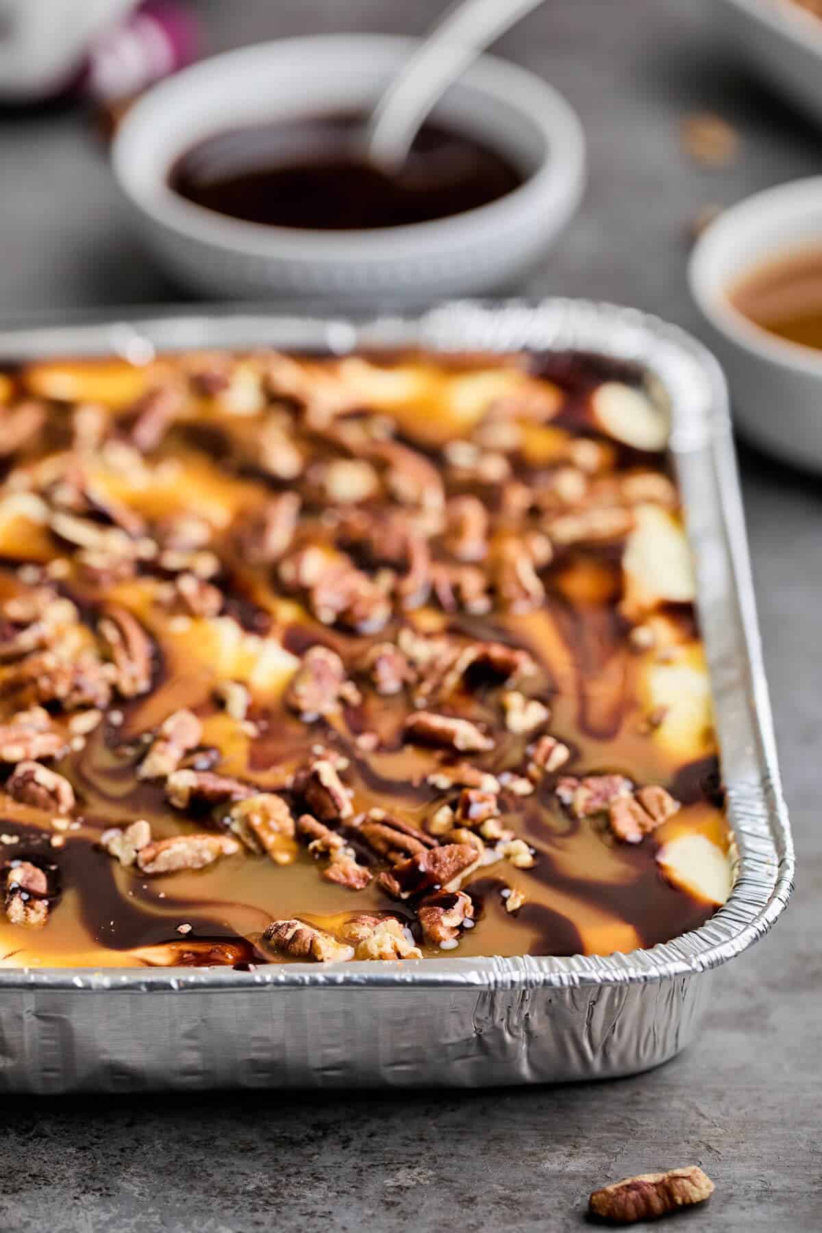 Side view of a sliced turtle cheesecake, showing layers of cookie crust, creamy cheesecake, and pecans.