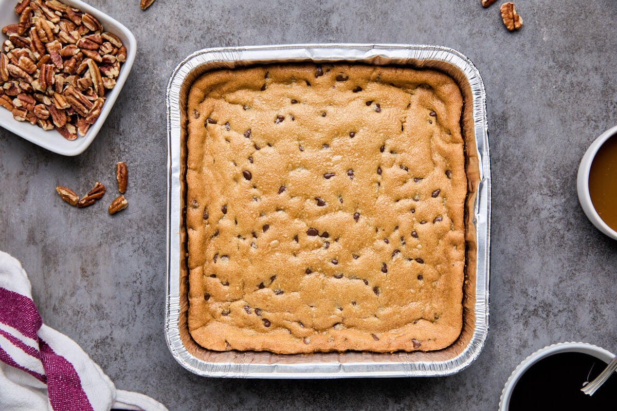 Baked chocolate chip cookie crust cooling in an 8x8-inch pan.