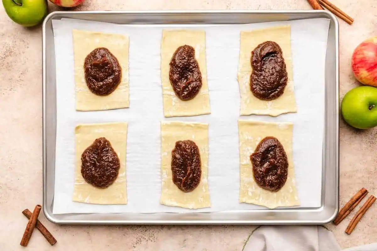 Scoops of apple butter placed onto unbaked puff pastry.