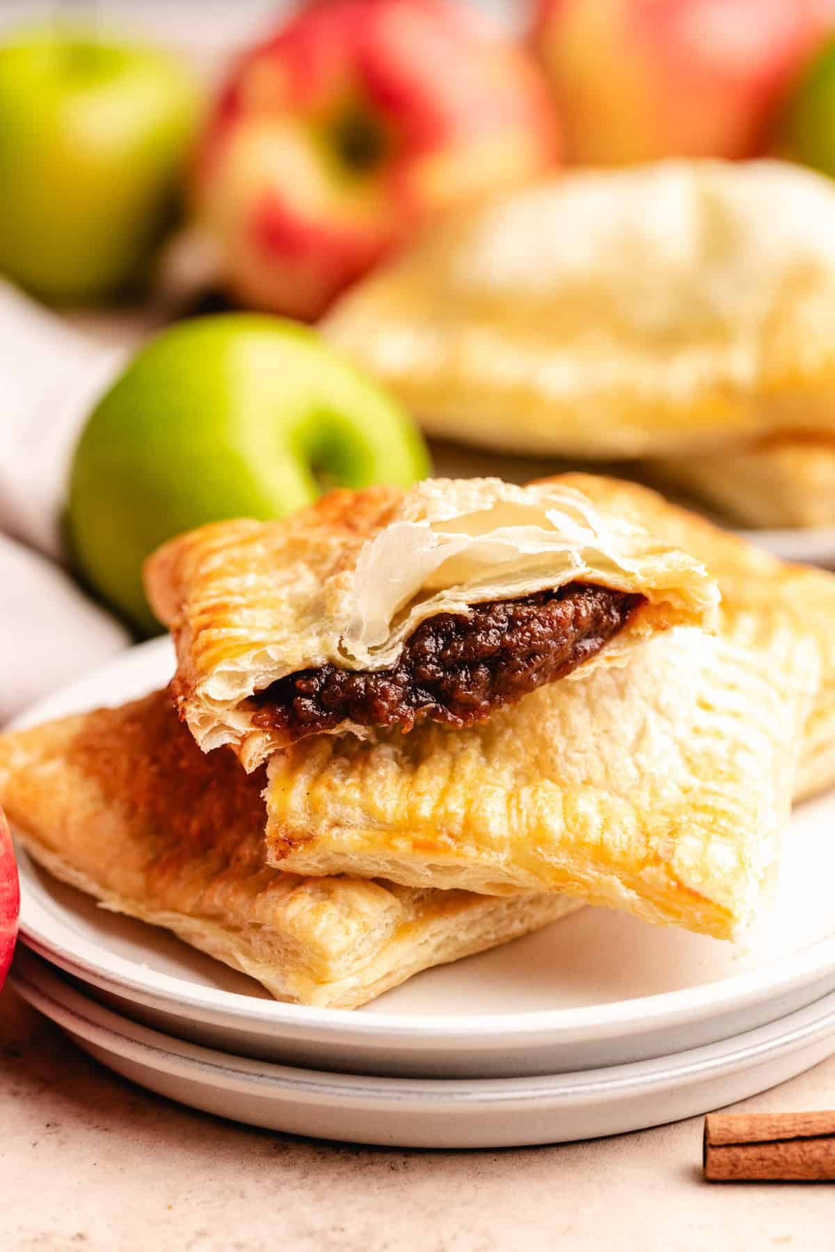 A stack of flaky baked apple butter hand pies on a plate.