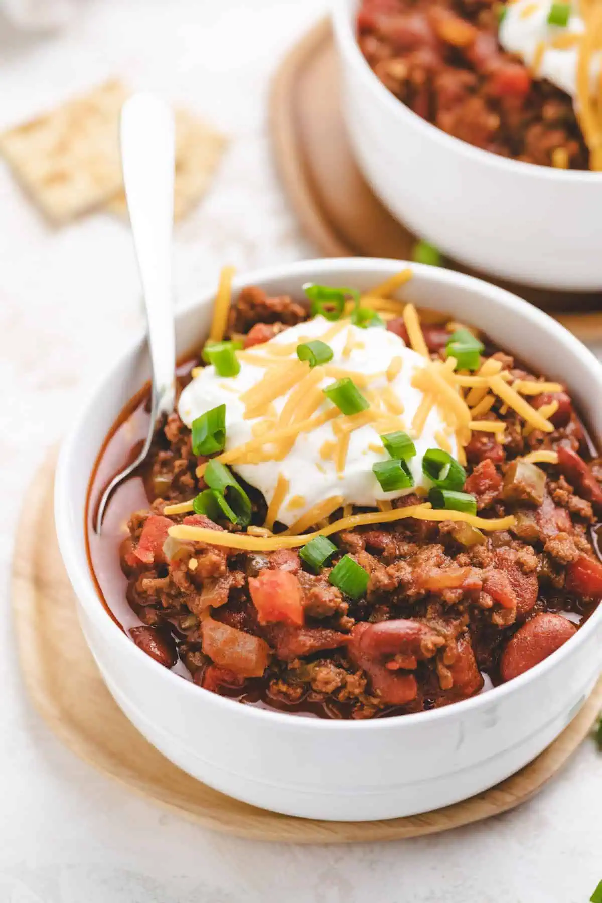 Close up of a bowl of ground beef and beans with a spoon.