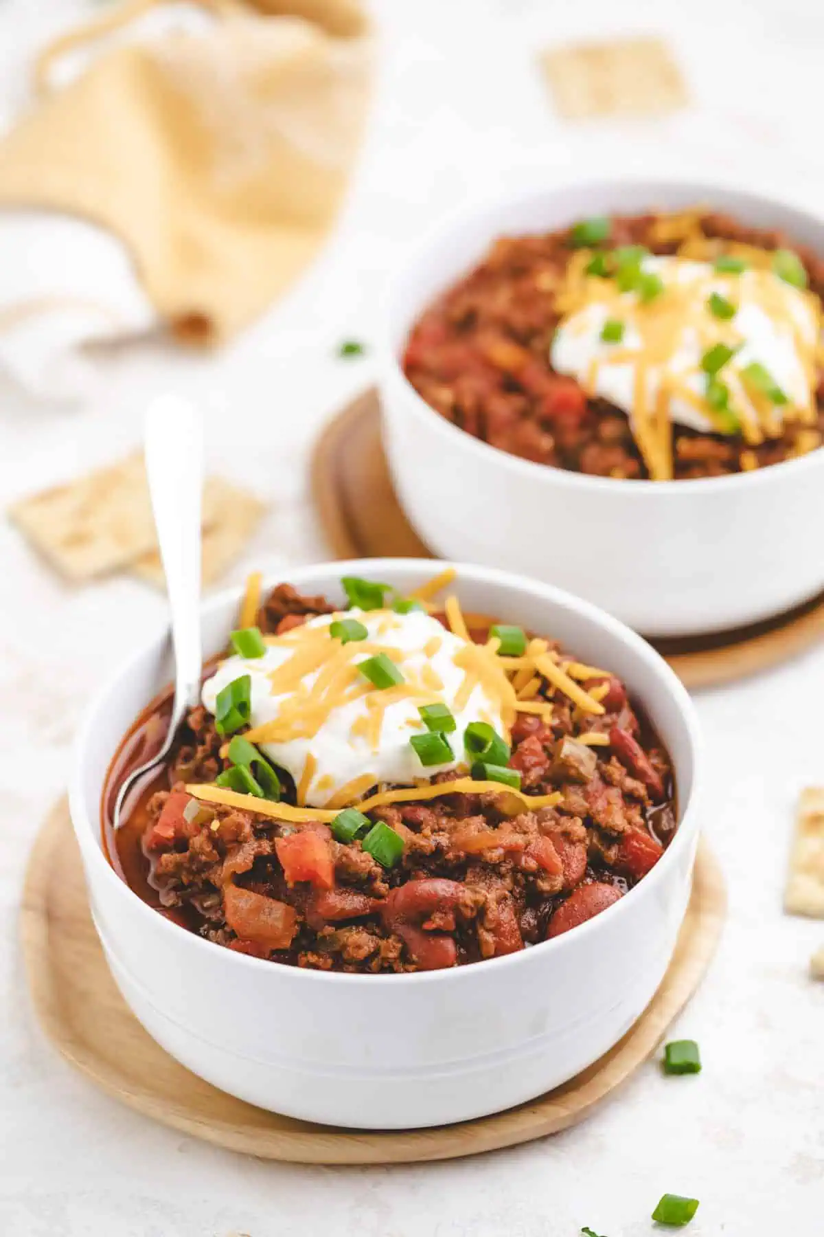 Two bowls filled with seasoned ground beef and beans, sour cream, and cheese.