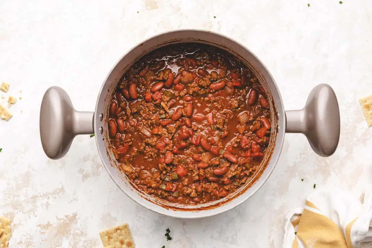 Easy chili recipe in a pot with ground beef, kidney beans, and diced tomatoes, simmering with spices like chili powder, cumin, and smoked paprika.