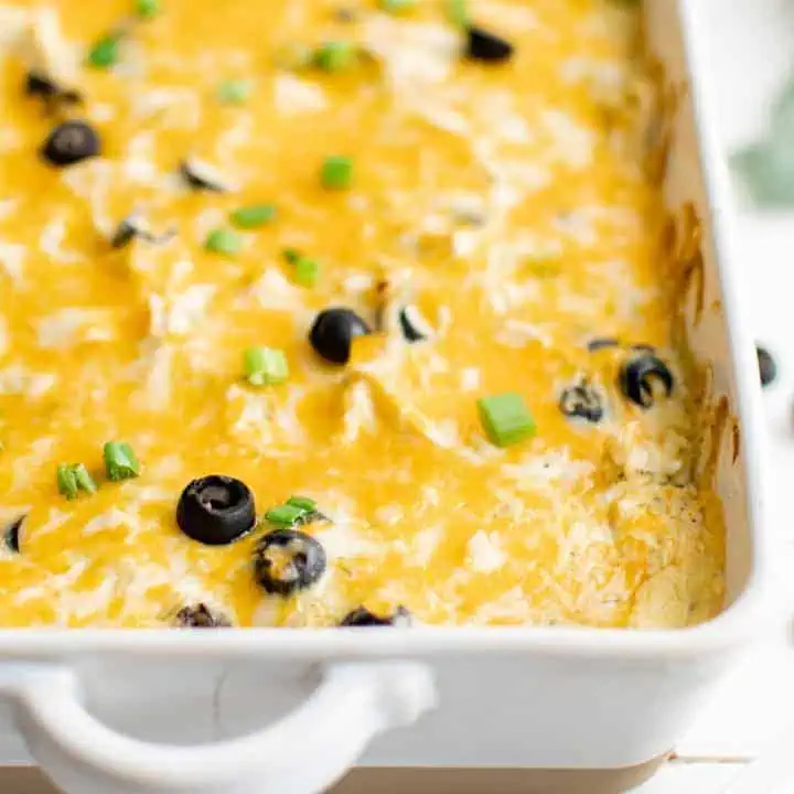 Close up of a green chile chicken casserole in a white baking dish.