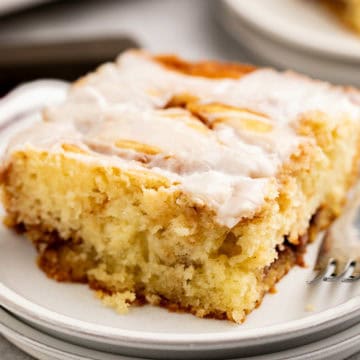 Close up view of cinnamon roll cake on white plates.