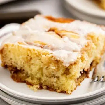 Close up view of cinnamon roll cake on white plates.