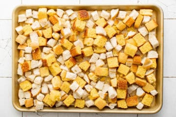 Cornbread and French bread pieces on a large sheet pan.