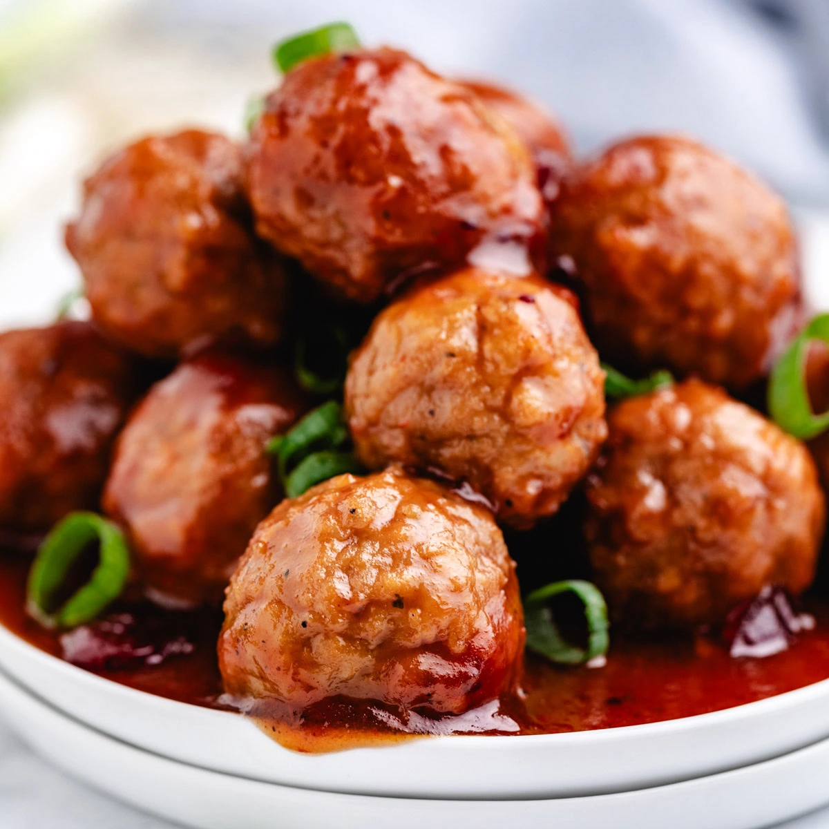 Close up view of cranberry bbq meatballs on a white dish.