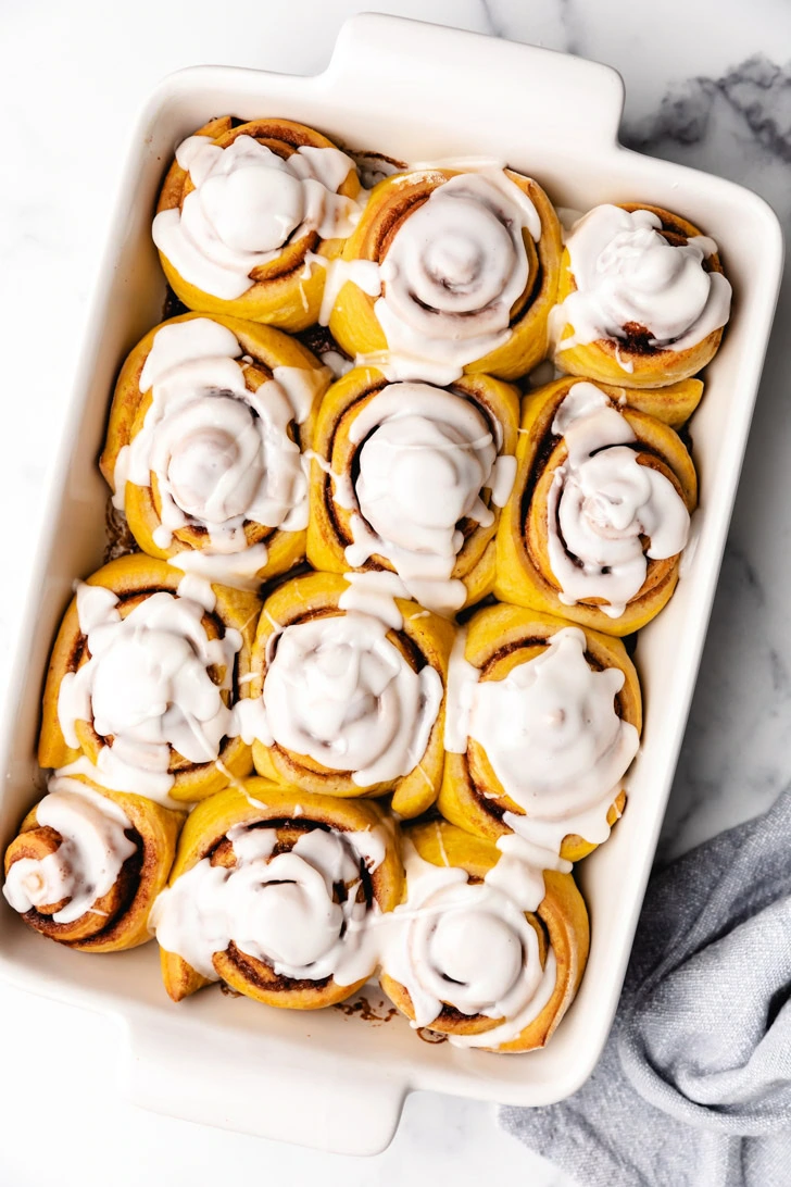 Top down view of glazed cinnamon rolls in a pan.