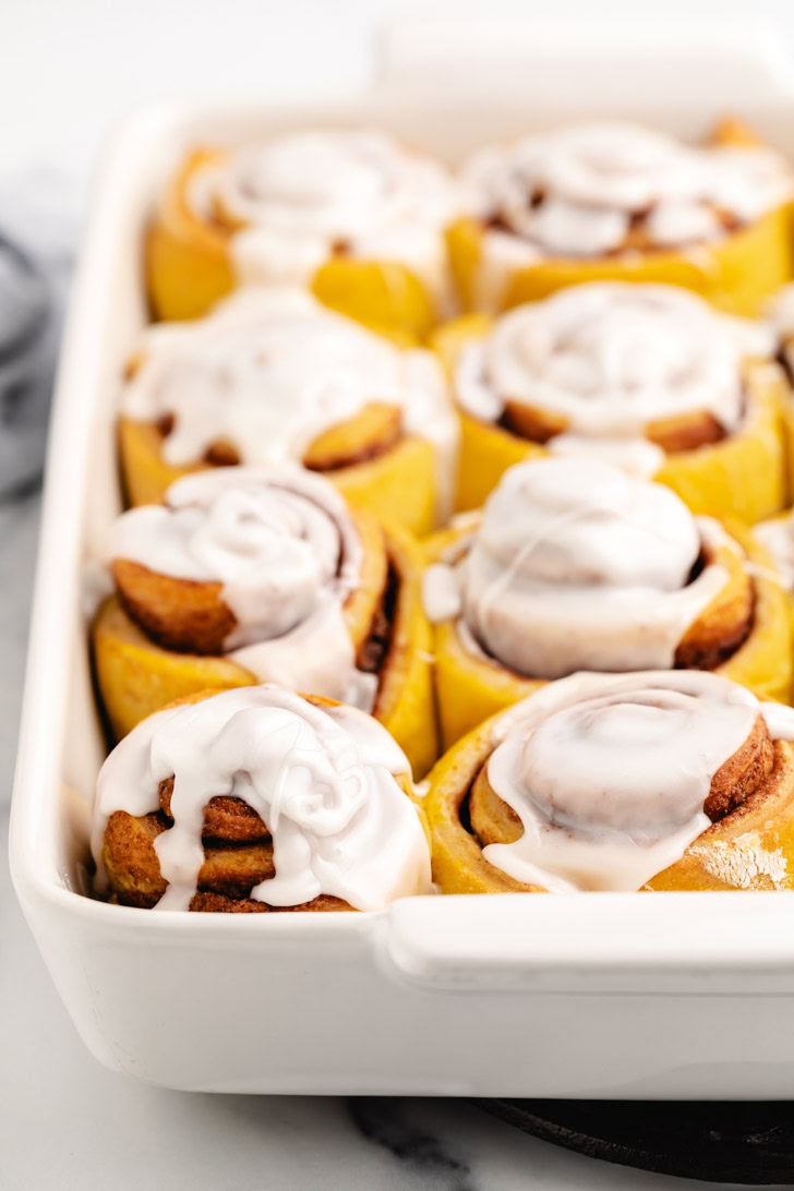 White baking pan filled with iced cinnamon rolls.