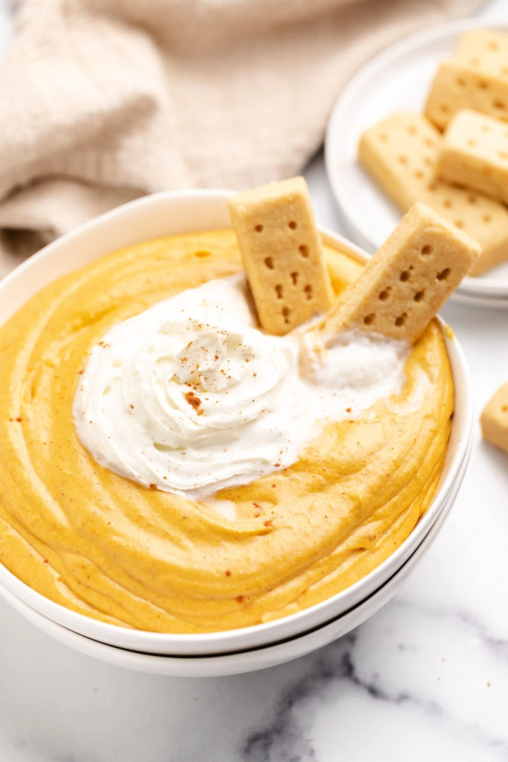 Shortbread cookies in a bowl of pumpkin cream cheese dip.