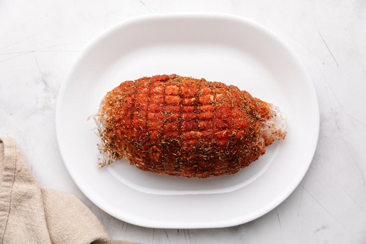 Seasoned turkey breast on a large plate.