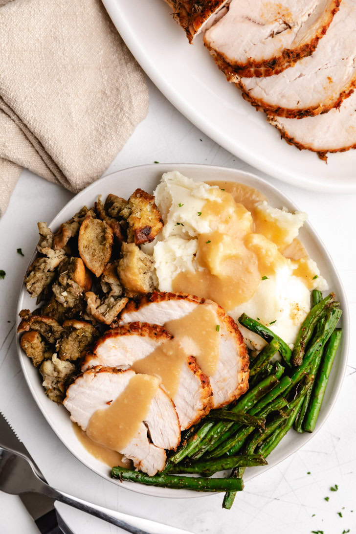 Overhead view of turkey, gravy, and sides on a plate.