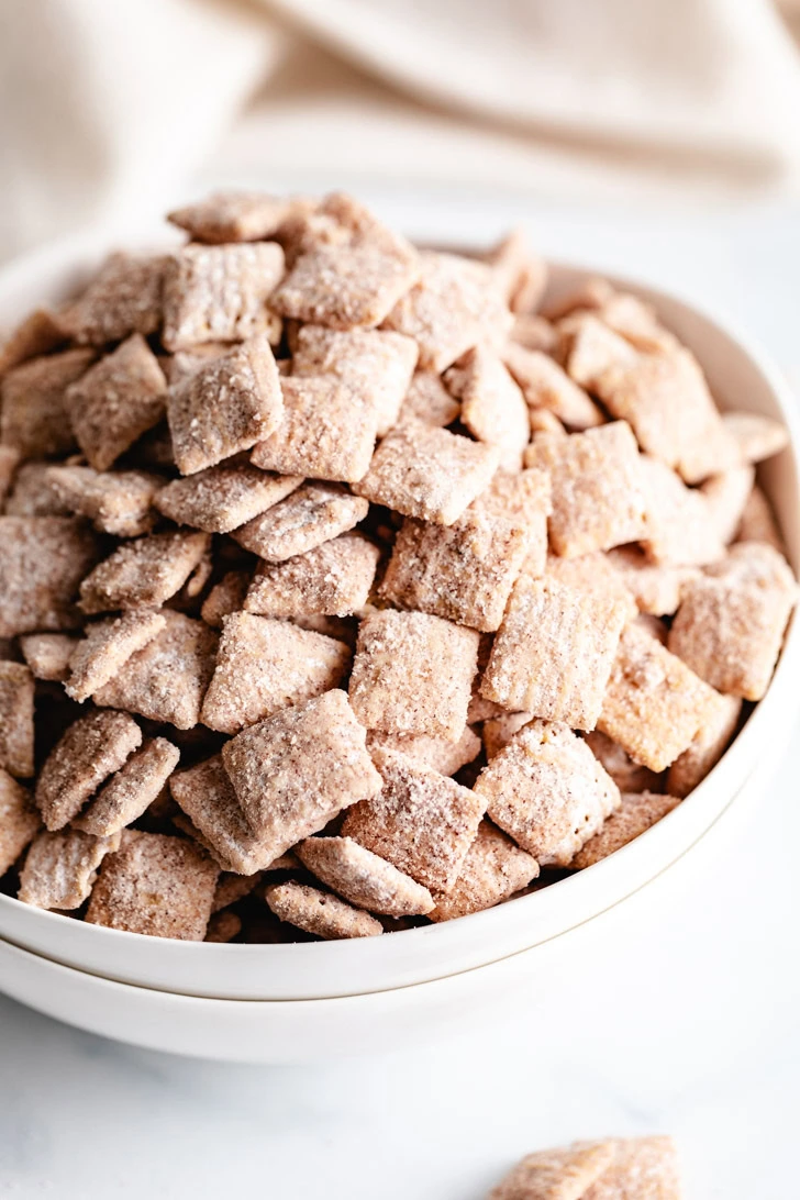 Close-up view of snickerdoodle muddy buddies with cinnamon sugar coating.