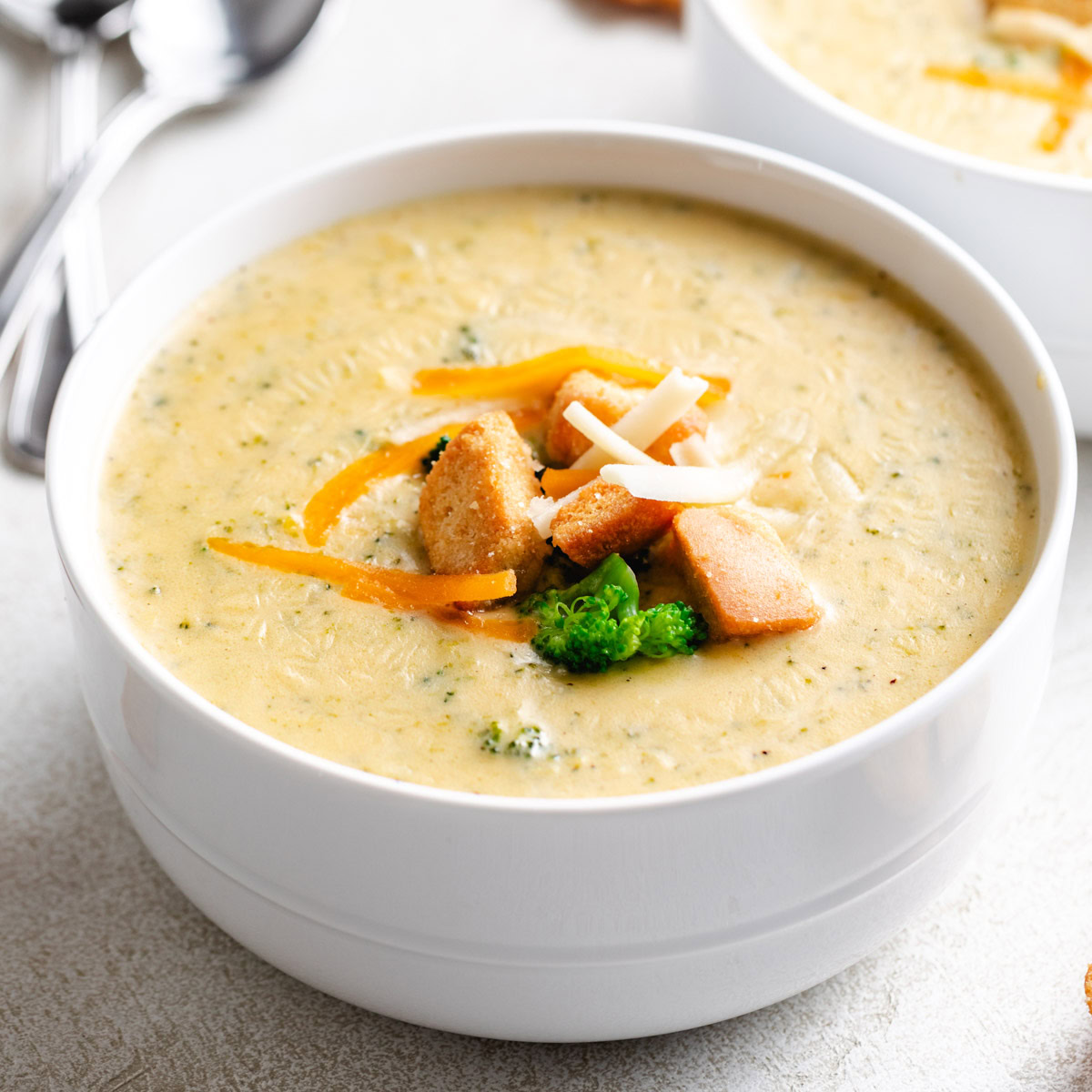 Close up view of a white bowl filled with broccoli cheddar soup.