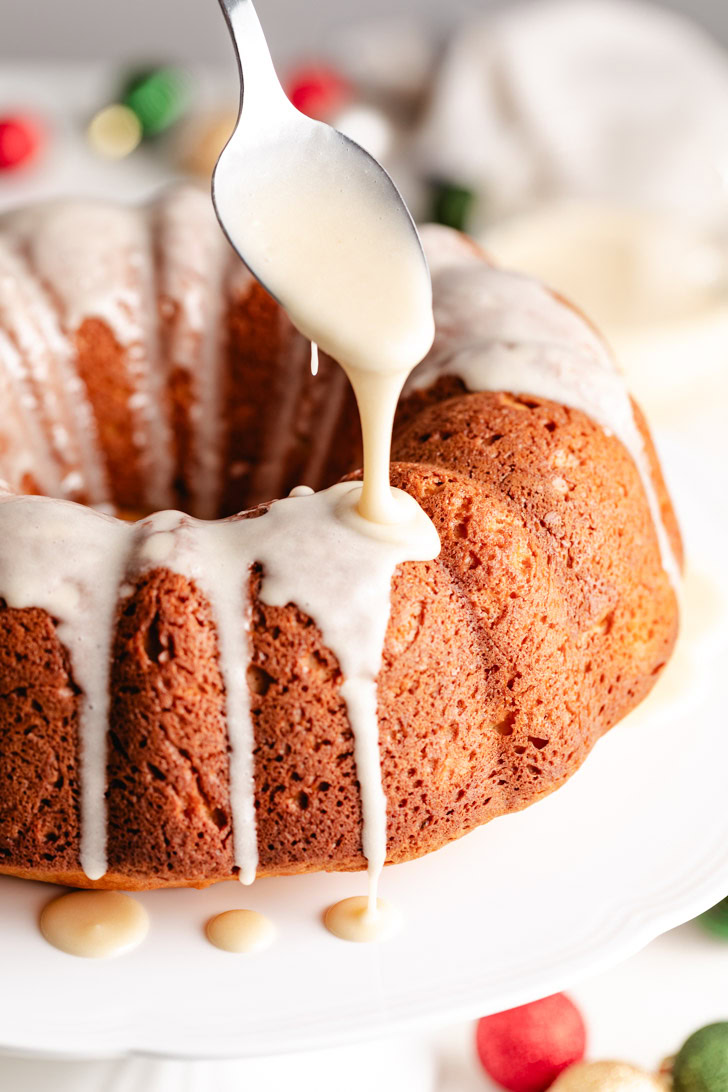 Spoon drizzling eggnog glaze on a cake.