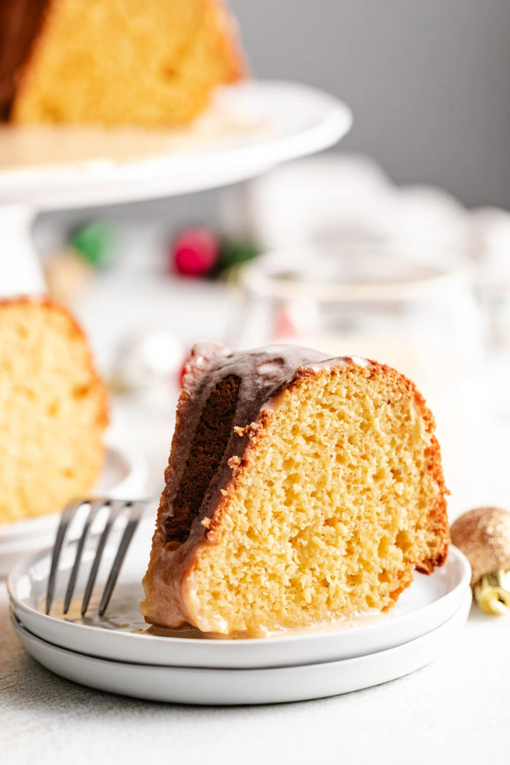 Slice of eggnog cake next to holiday ornaments.