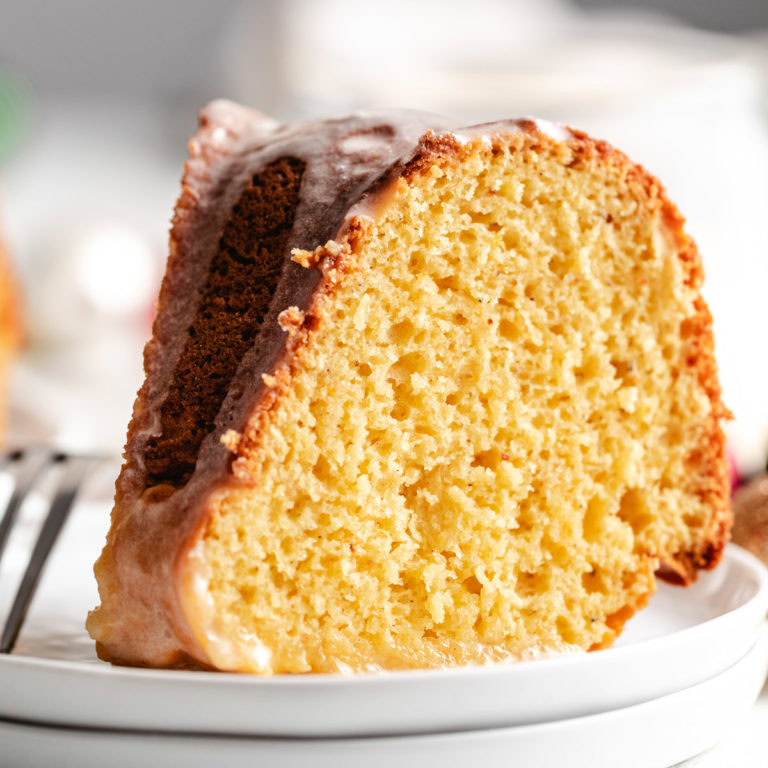 Close up view of an eggnog cake recipe on a stack of white plates.