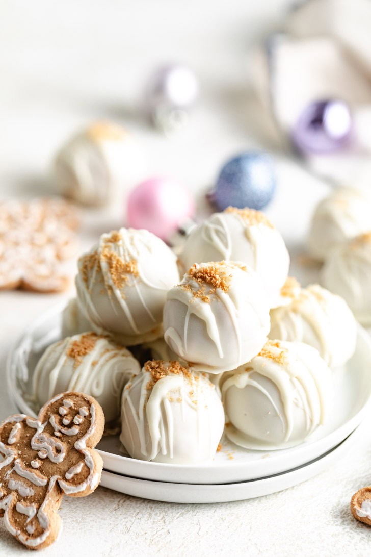 Plate of truffles surrounded by christmas ornaments.