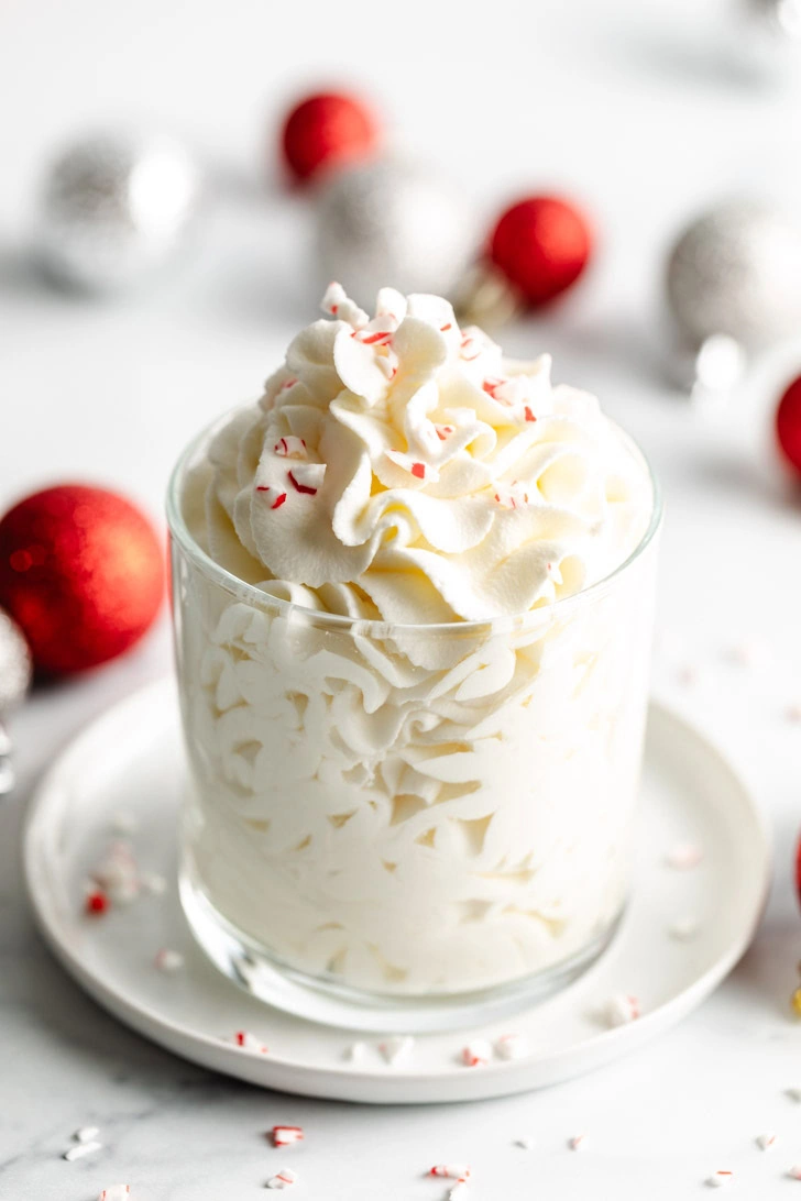 Christmas ornaments scattered around a glass of whipped cream.