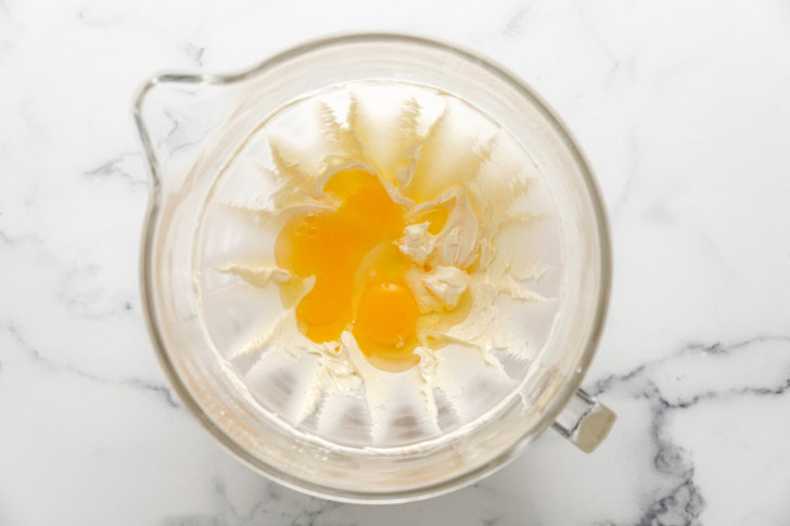 Eggs added to a bowl of creamed butter and sugar.