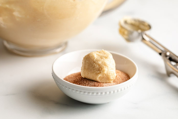 Dough ball being rolled in cinnamon sugar.