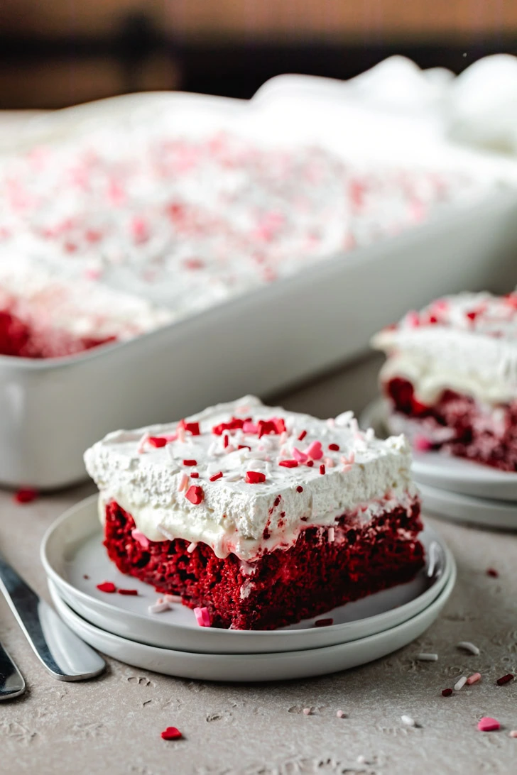 Cake on a stack of plates next to forks.