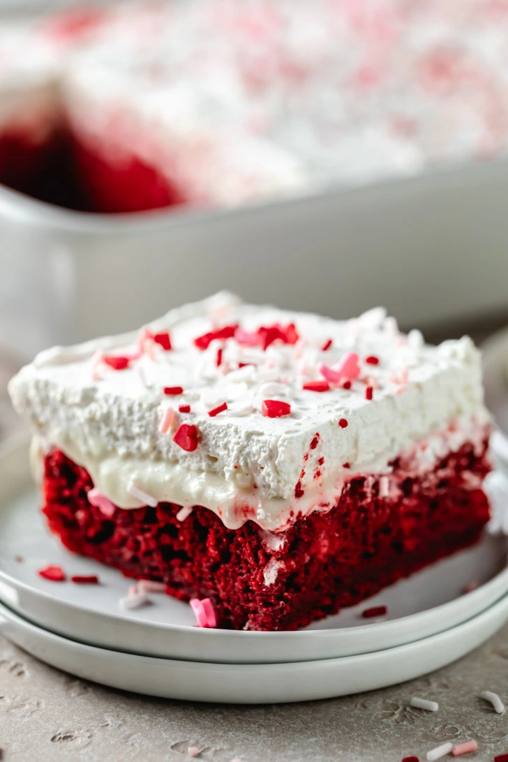 Red velvet cake on a stack of white plates.