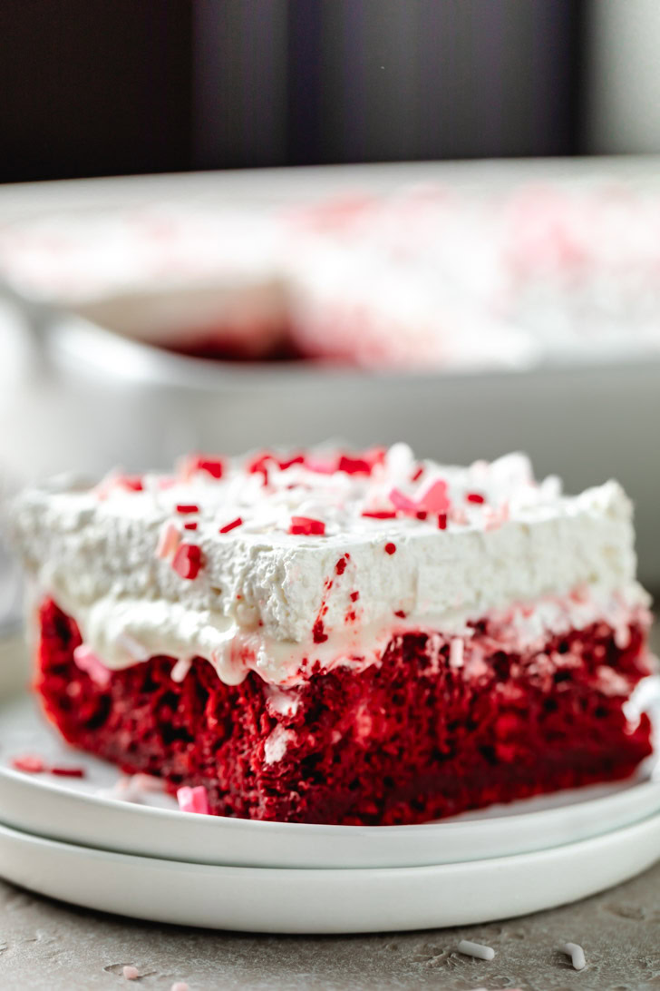 Close up view of a slice of cake with cool whip frosting.