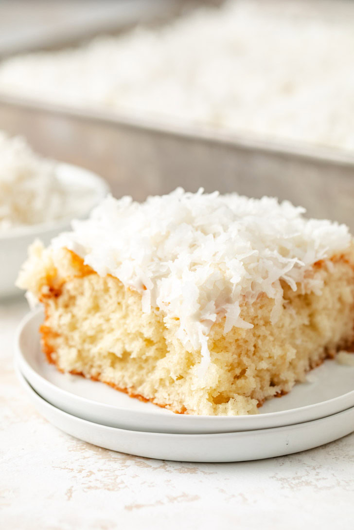 A slice of cake covered with coconut flakes and frosting.