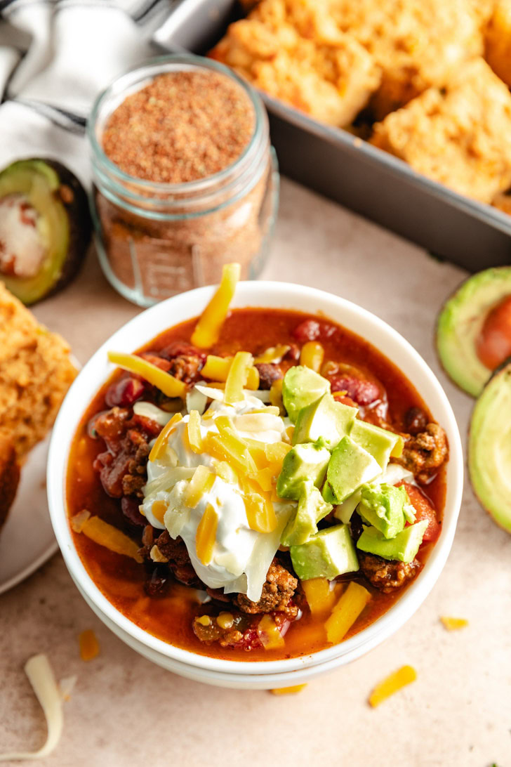 A close-up of slow cooker chili in a bowl with toppings.