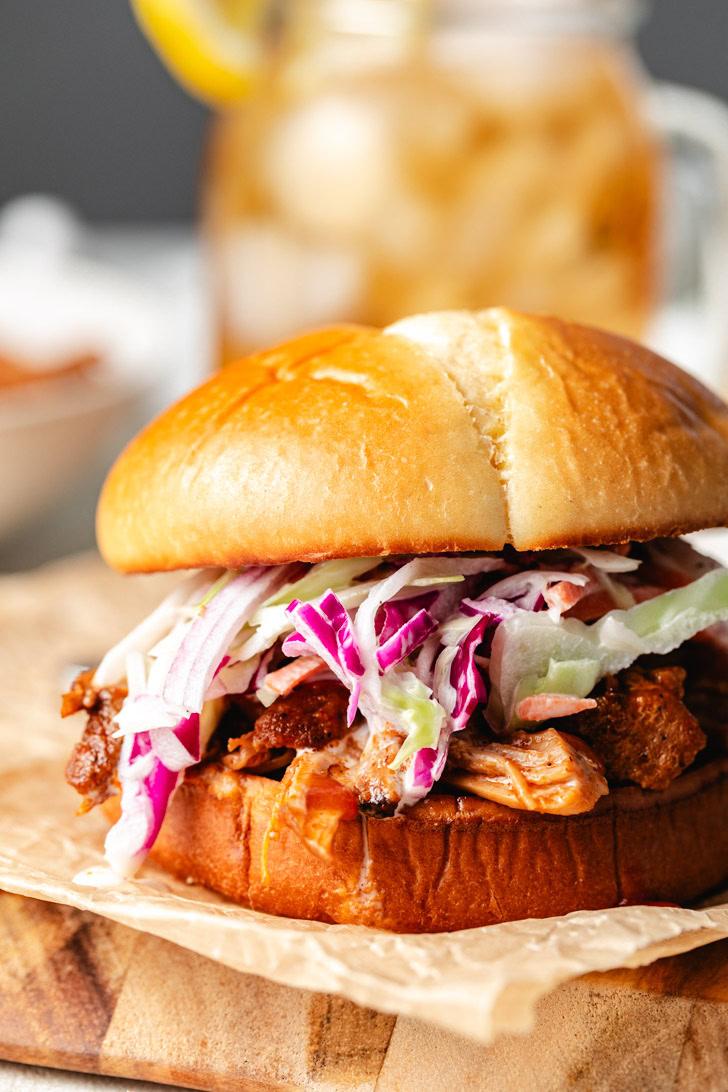 Slow cooker pulled pork sandwich with coleslaw, served with a side of bbq sauce.