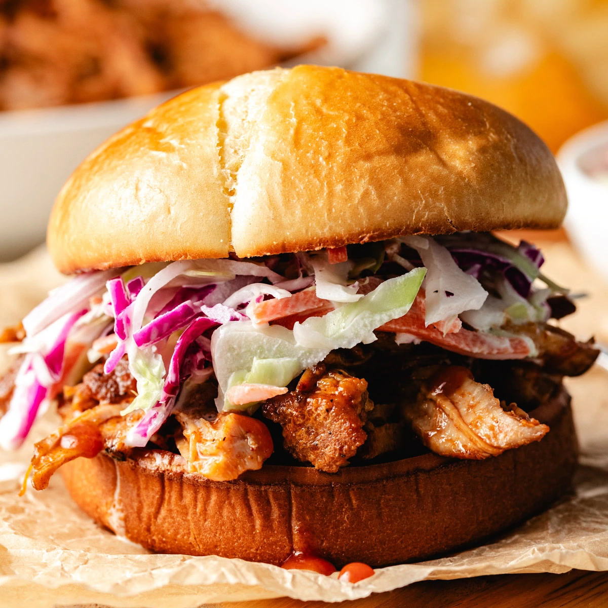 Bbq pulled pork sandwich with coleslaw on parchment paper.