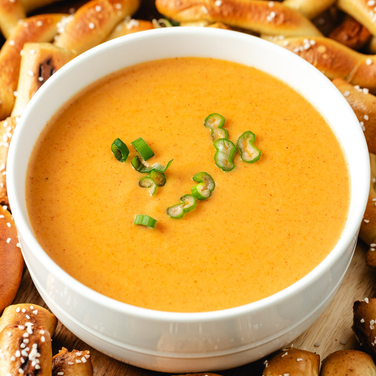 A bowl of creamy beer cheese dip garnished with green onions.